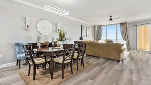 Una sala de estar moderna con comedor, ventanas amplias y ventilador de techo.
