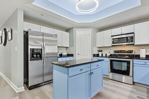Enjoy cooking in this well-equipped kitchen with a central island, refrigerator, microwave, and oven.