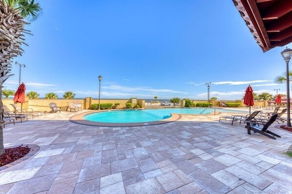 Relax by the pool surrounded by comfortable lounge chairs and shaded areas.