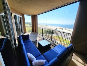 Enjoy the ocean view from this balcony with a comfortable seating area and table.