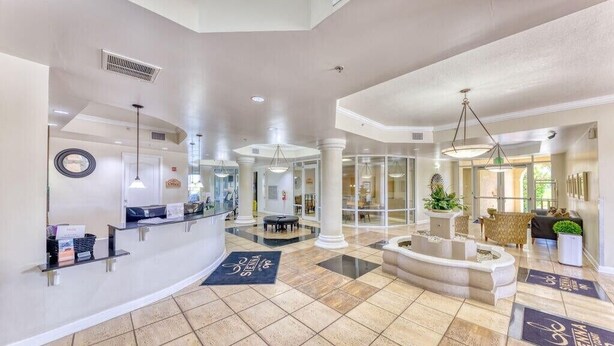 Un vestíbulo amplio con mostrador de recepción, zona de estar y una fuente central.