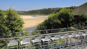 A view of a beach with a river in the background, surrounded by trees and a building with a tiled roof. - Blue Lagoon Hotel and Conference Centre (East London)