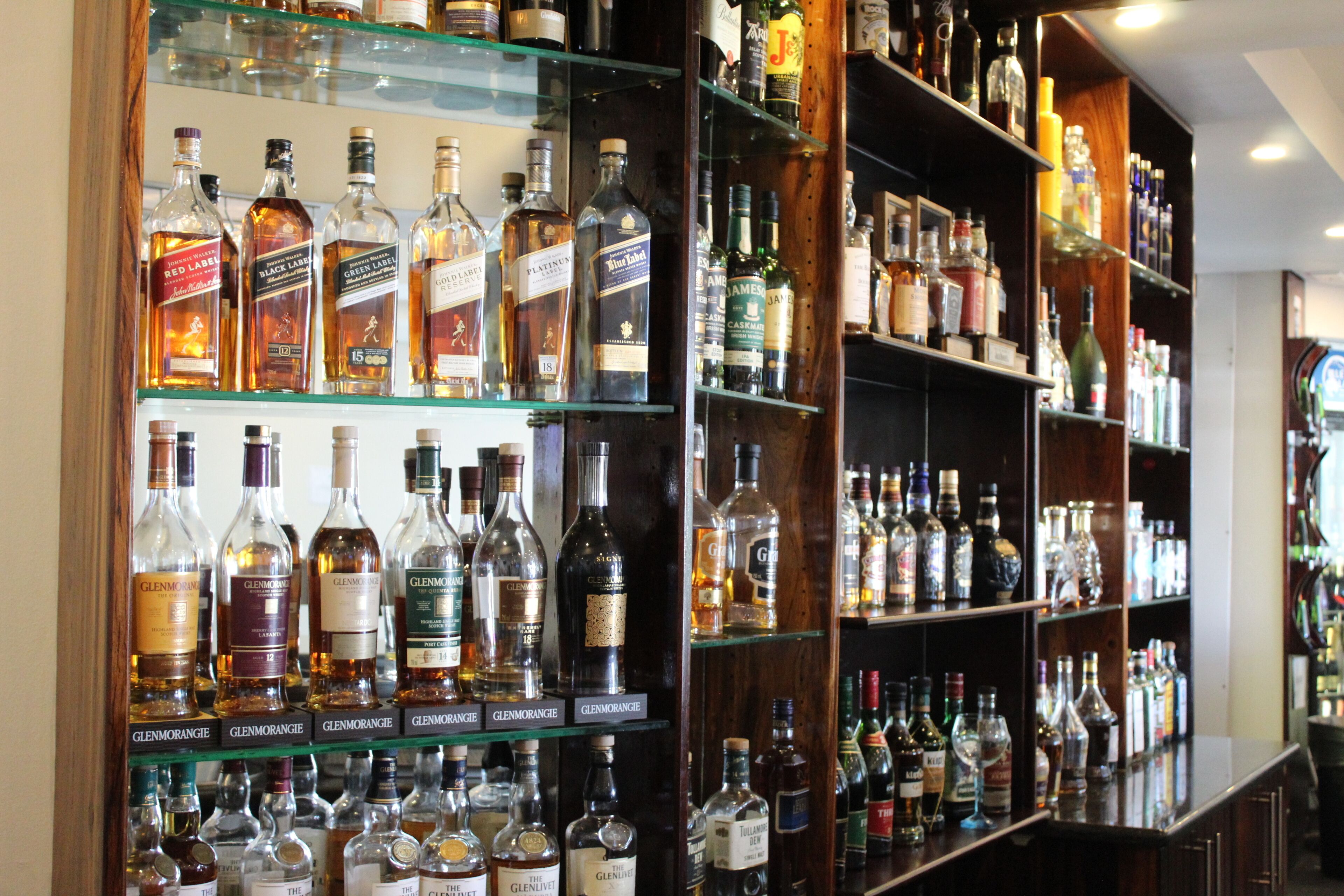 A bar with shelves stocked with various liquor bottles.