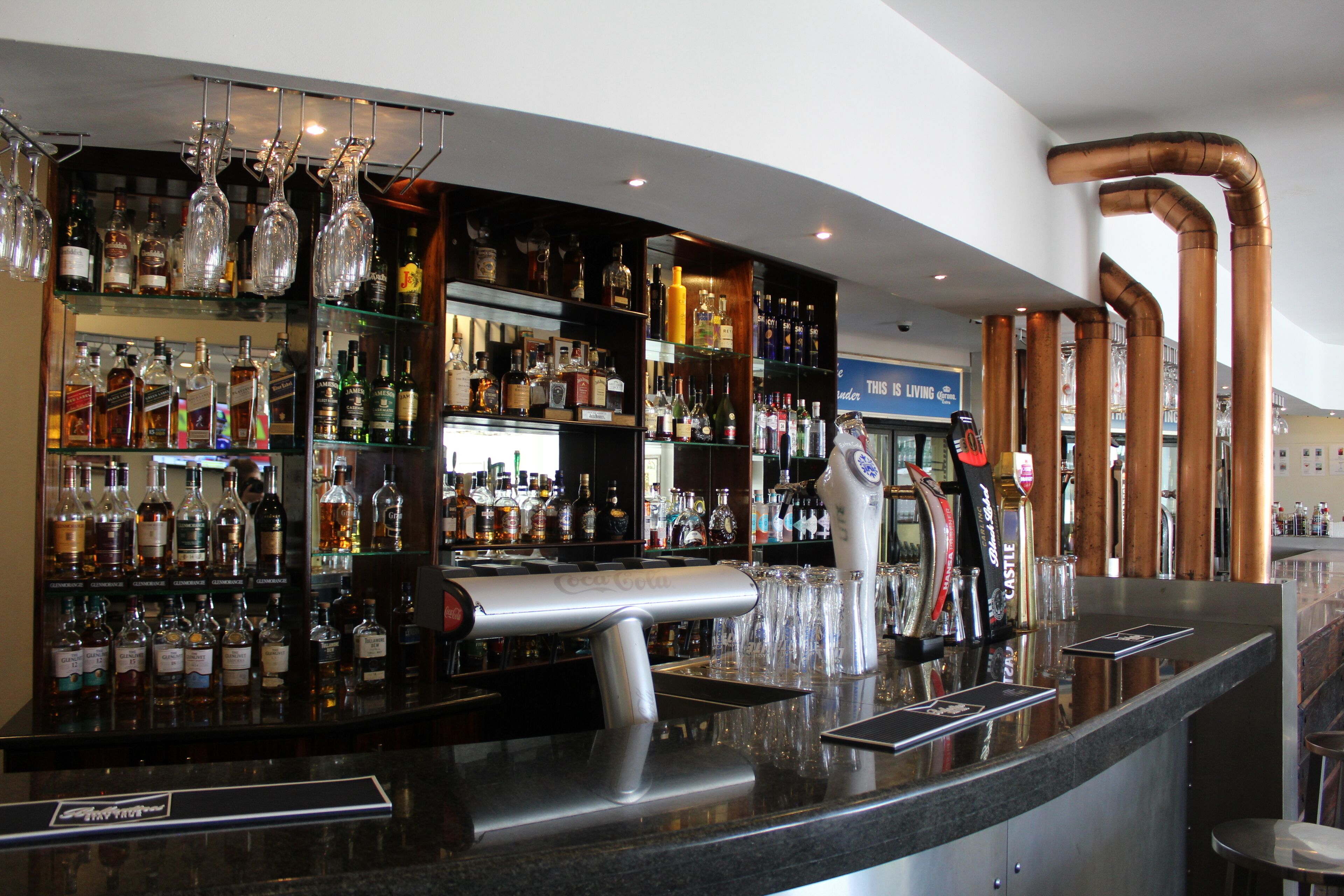 A bar area with shelves of liquor bottles, a bar counter, and a coffee machine.