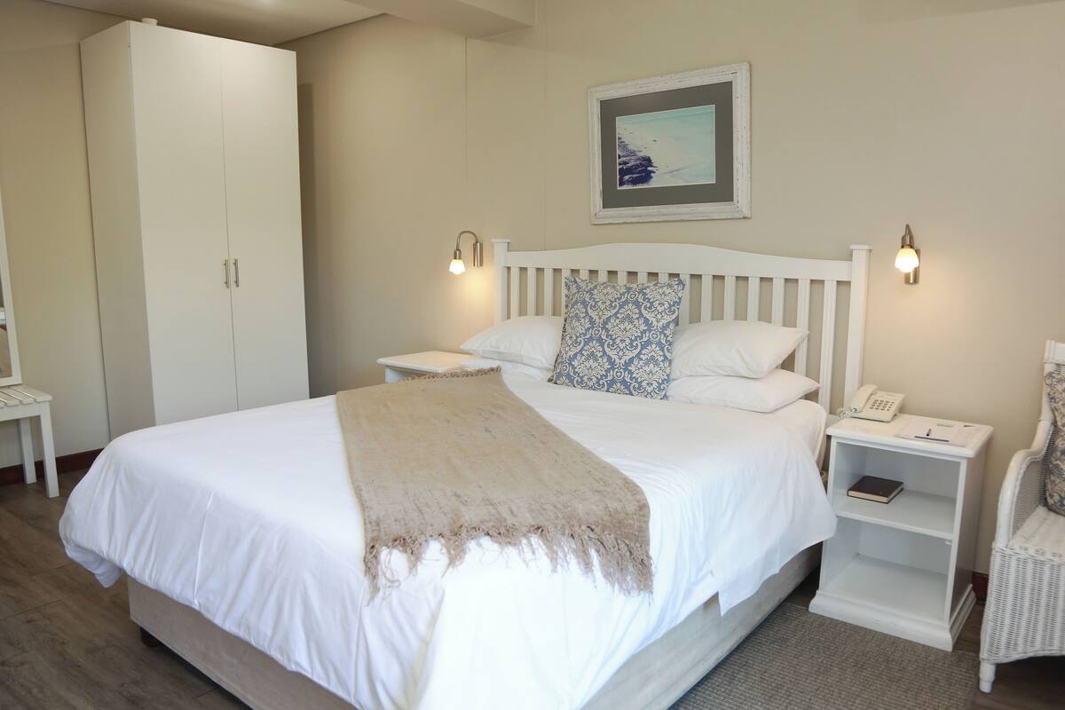 A bedroom with a large bed, bedside tables, a wardrobe, and a framed picture on the wall.