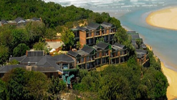 A coastal hotel with multiple buildings, surrounded by dense greenery and a beach. - Blue Lagoon Hotel and Conference Centre (East London)