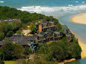 A coastal hotel with multiple buildings, surrounded by dense greenery and a beach. - Blue Lagoon Hotel and Conference Centre (East London)