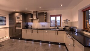 A modern kitchen with a black countertop, stainless steel appliances, and a window with a view. - Townfoot Barn (Windermere)