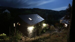 A house with a sloped roof, a stone wall, and a small garden area. - Townfoot Barn (Windermere)