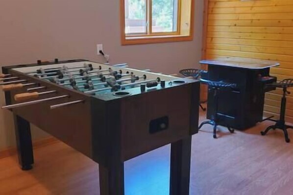 Una mesa de futbolín en una habitación con ventana y pared de madera.