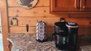A kitchen with a coffee maker, a kettle, and a clock on the wall.