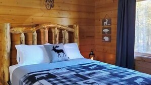 A wooden cabin room with a bed, a deer head decoration, and animal symbols on the wall.