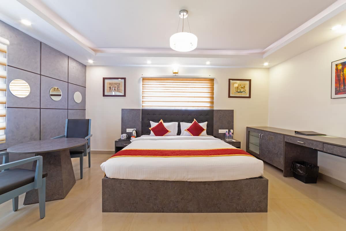 A modern bedroom with a large bed, a desk, and a seating area.