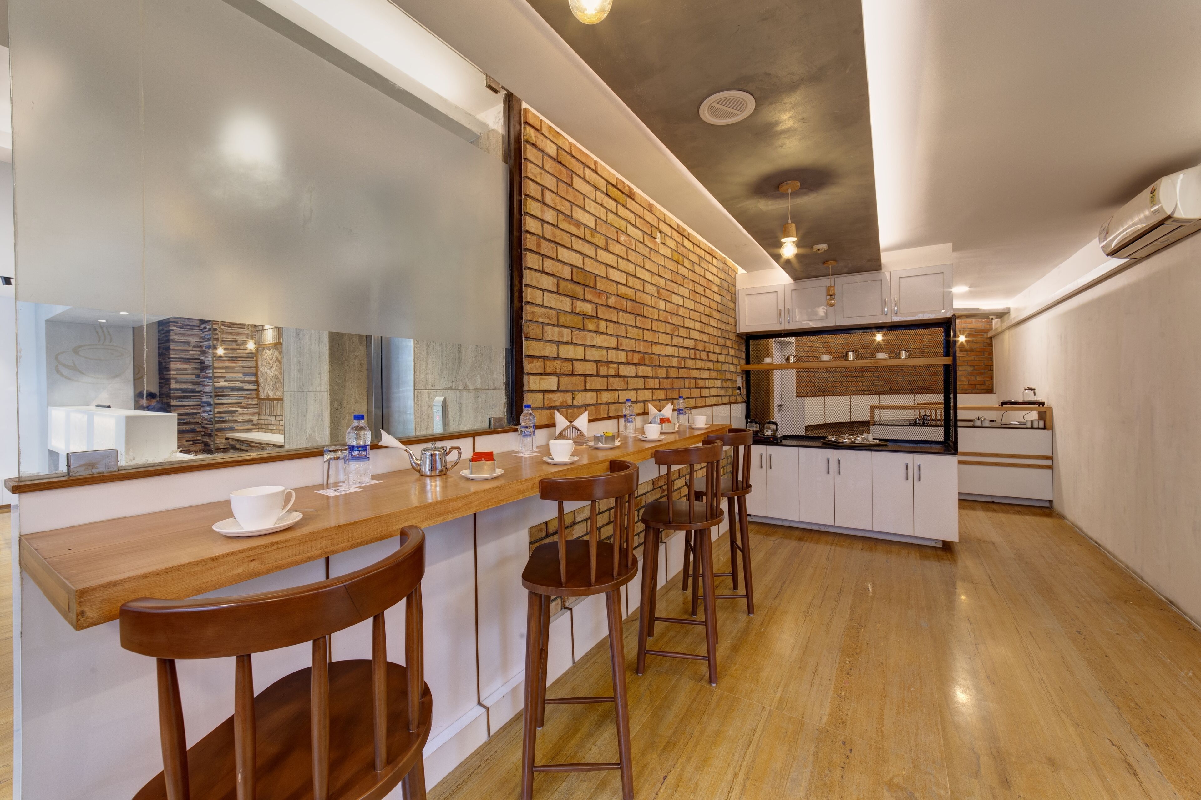 A modern kitchen with a wooden bar area, white cabinets, and a brick accent wall.