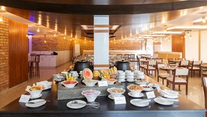 Un montaje tipo bufé con diferentes alimentos y un área de comedor con mesas y sillas.