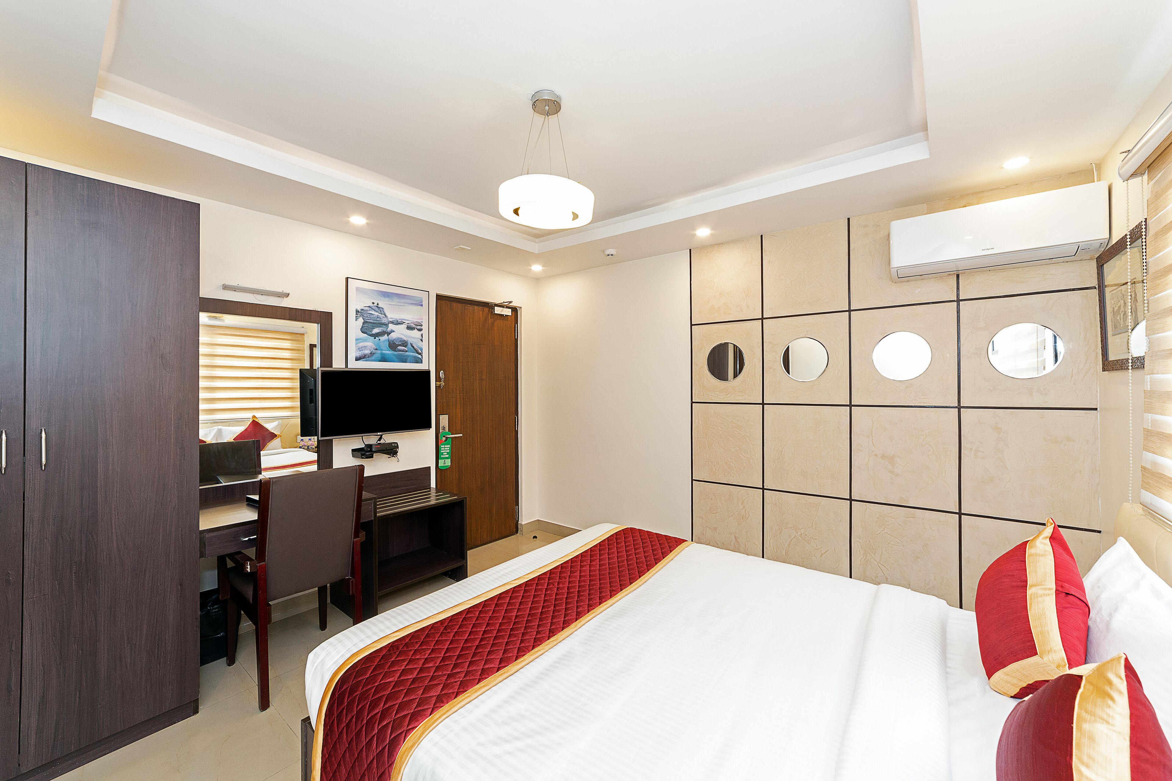 A hotel room with a bed, a desk, a chair, a television, and a wardrobe.