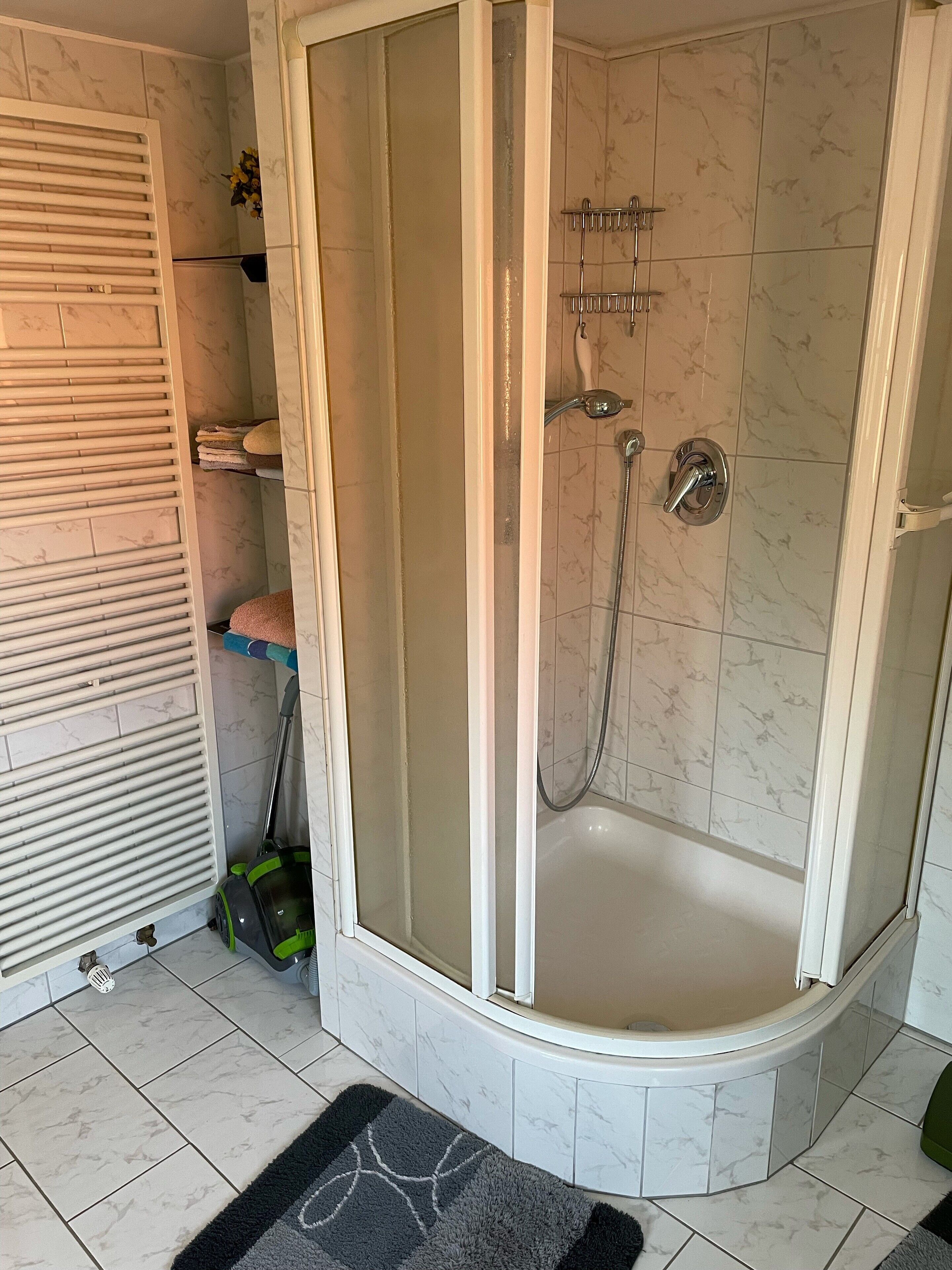 Eine Eckdusche mit Glastür, eine Badewanne und ein Handtuchhalter.