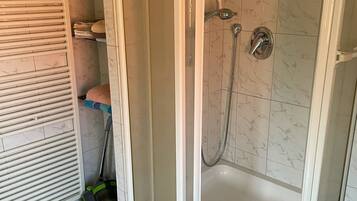 Eine Eckdusche mit Glastür, eine Badewanne und ein Handtuchhalter.