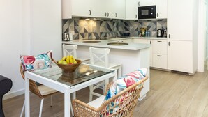 Una cocina moderna con armarios blancos, un microondas y un frutero en la encimera.
