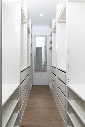 Ein schmales Entree mit weißen Regaleinheiten an beiden Seiten und einem Spiegel an der Wand.