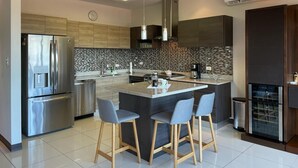 Cocina moderna con una isla central, electrodomésticos de acero inoxidable y salpicadero de azulejos.