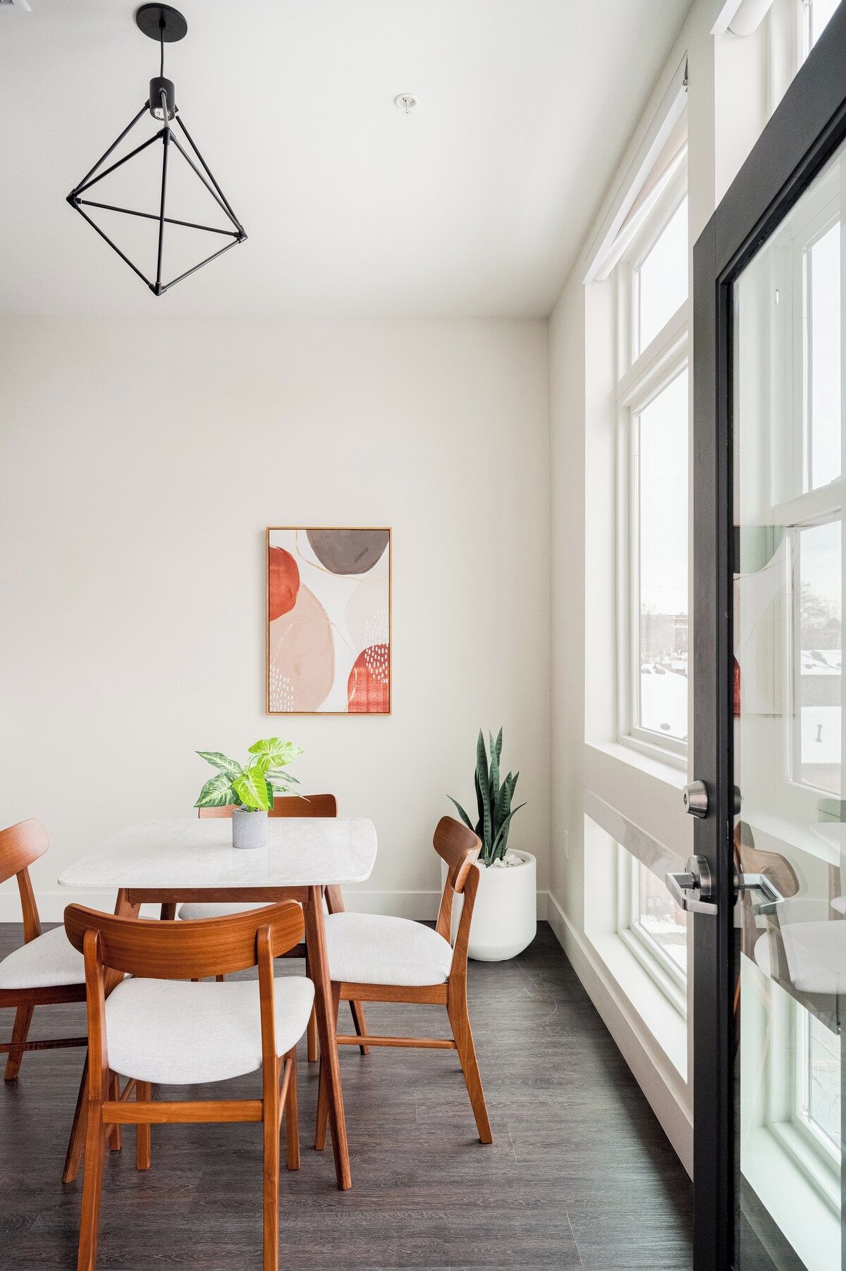 A modern dining area with a table, chairs, and a hanging light fixture.