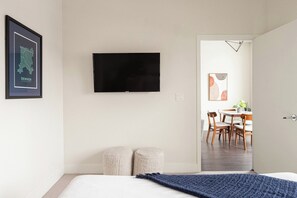 Ett hotellrum med en säng, en platt-TV som är monterad på väggen, en inramad karta över Denver och en matplats som syns genom en öppen dörr.