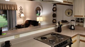 Una cucina compatta con un fornello, una macchina da caffè e un frullatore sul piano di lavoro.