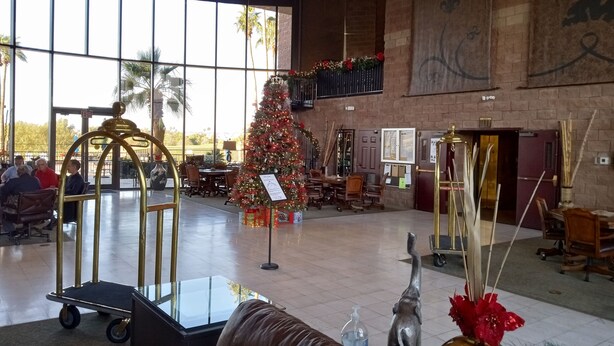 Un'ampia hall con un grande albero di Natale, una reception e un'area salotto con un divano in pelle marrone.