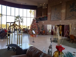A spacious lobby with a large Christmas tree, a reception desk, and a seating area with a brown leather couch.