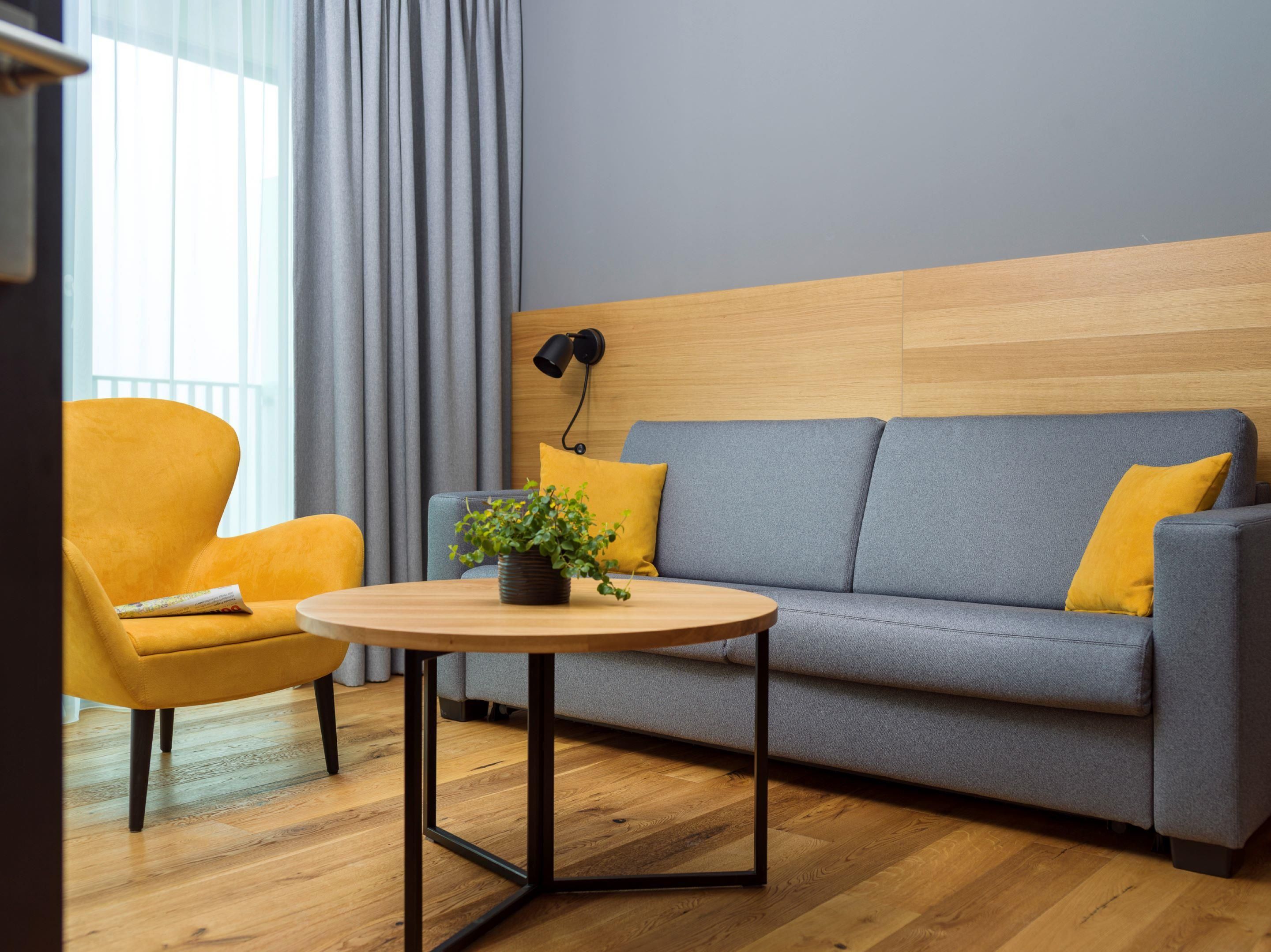 A modern living room with a sofa, armchair, and round table.