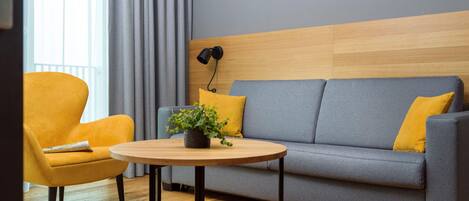 A modern living room with a sofa, armchair, and round table.