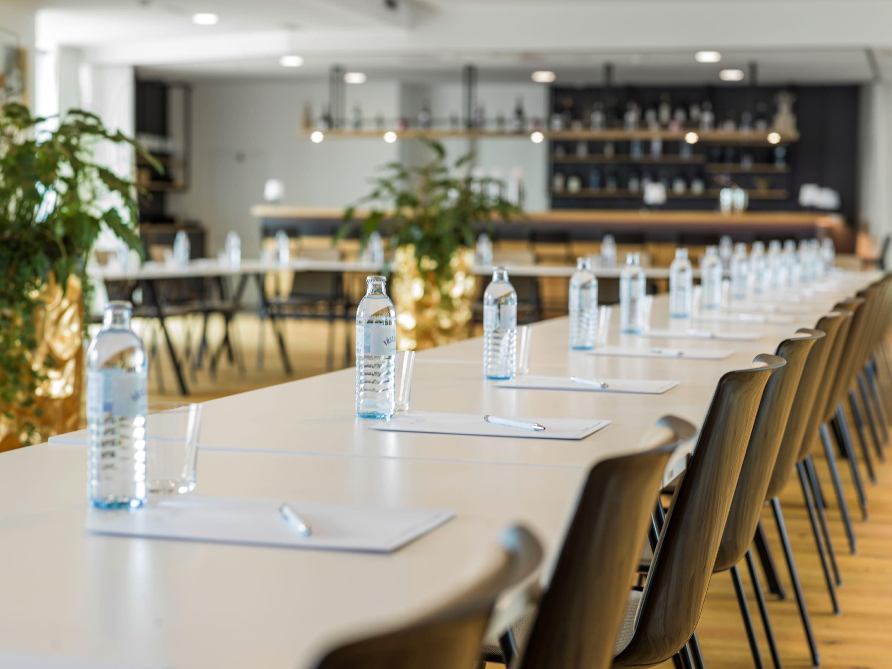 A conference room with long tables, water bottles, and chairs.