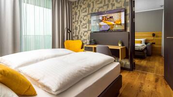 Una habitación de hotel con cama, escritorio, silla y vistas a otra habitación.