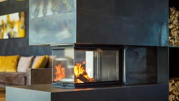 A modern fireplace with a glass front, a dark-toned mantel, and a log storage area to the right.