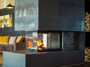 A modern fireplace with a glass front, a dark-toned mantel, and a log storage area to the right. - Best Western Parkhotel Hagenberg (Hagenberg im Mühlkreis)