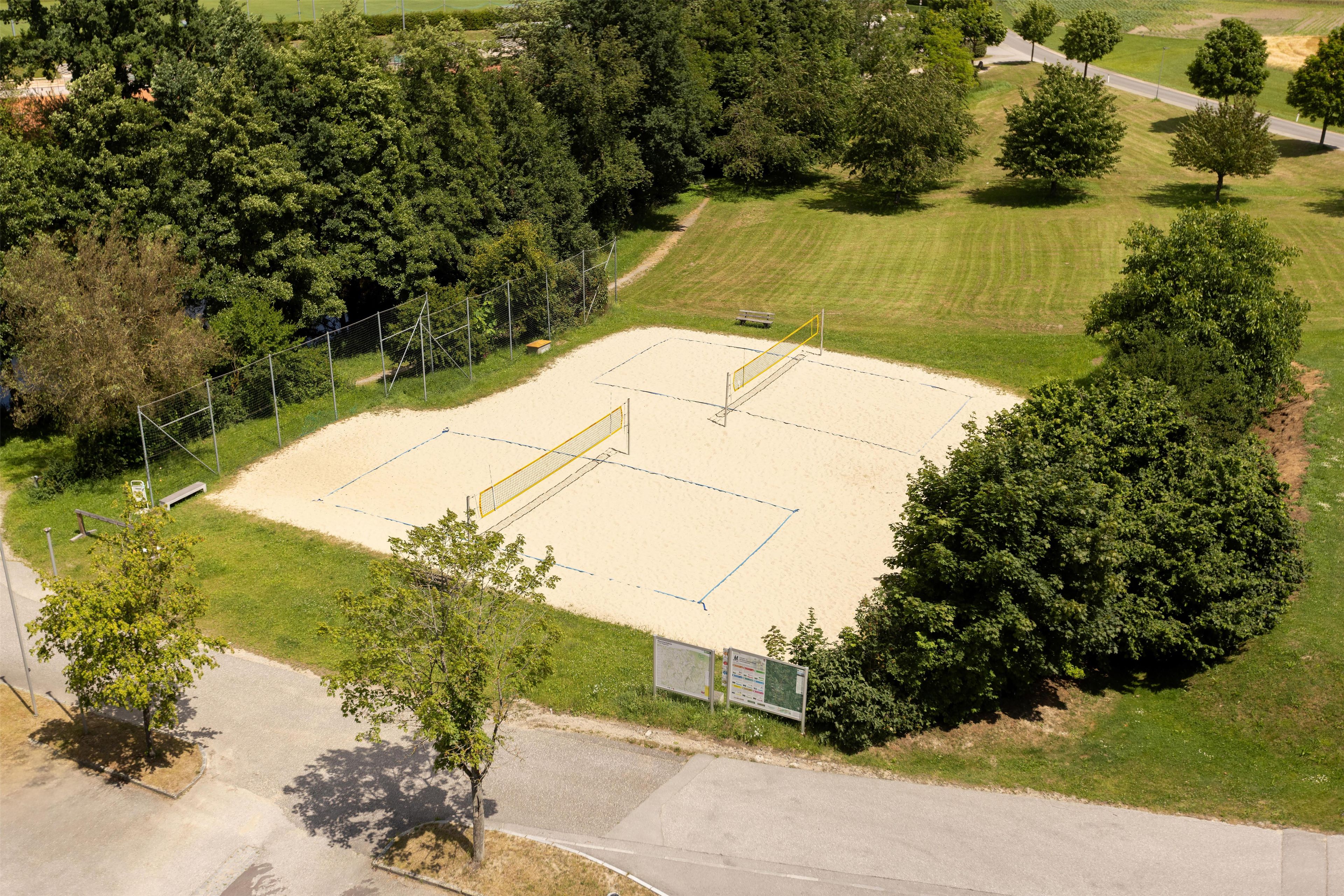 An aerial view of a sports court surrounded by trees and a road.