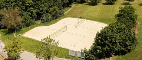 An aerial view of a sports court surrounded by trees and a road.