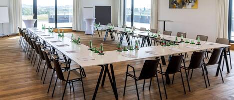 Un salón de conferencias con una larga mesa, sillas y una pantalla para proyector.