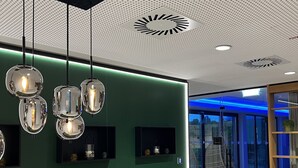 A modern reception area with a green wall, hanging spherical pendant lights, and a wooden slatted counter. - Best Western Parkhotel Hagenberg (Hagenberg im Mühlkreis)