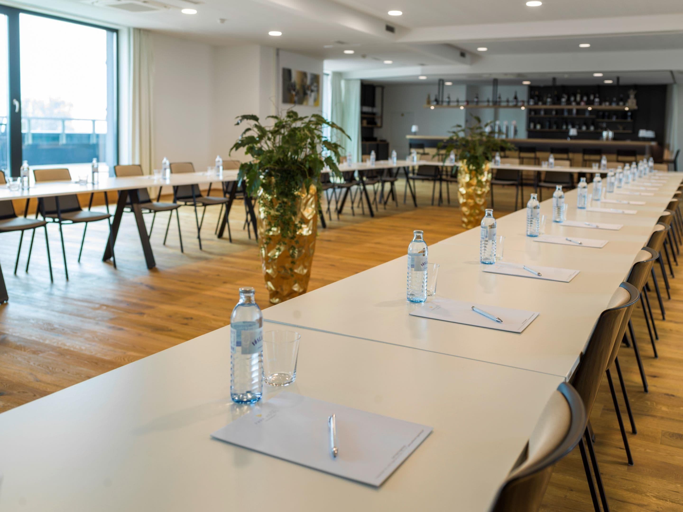 A conference room with long tables, water bottles, and notepads.