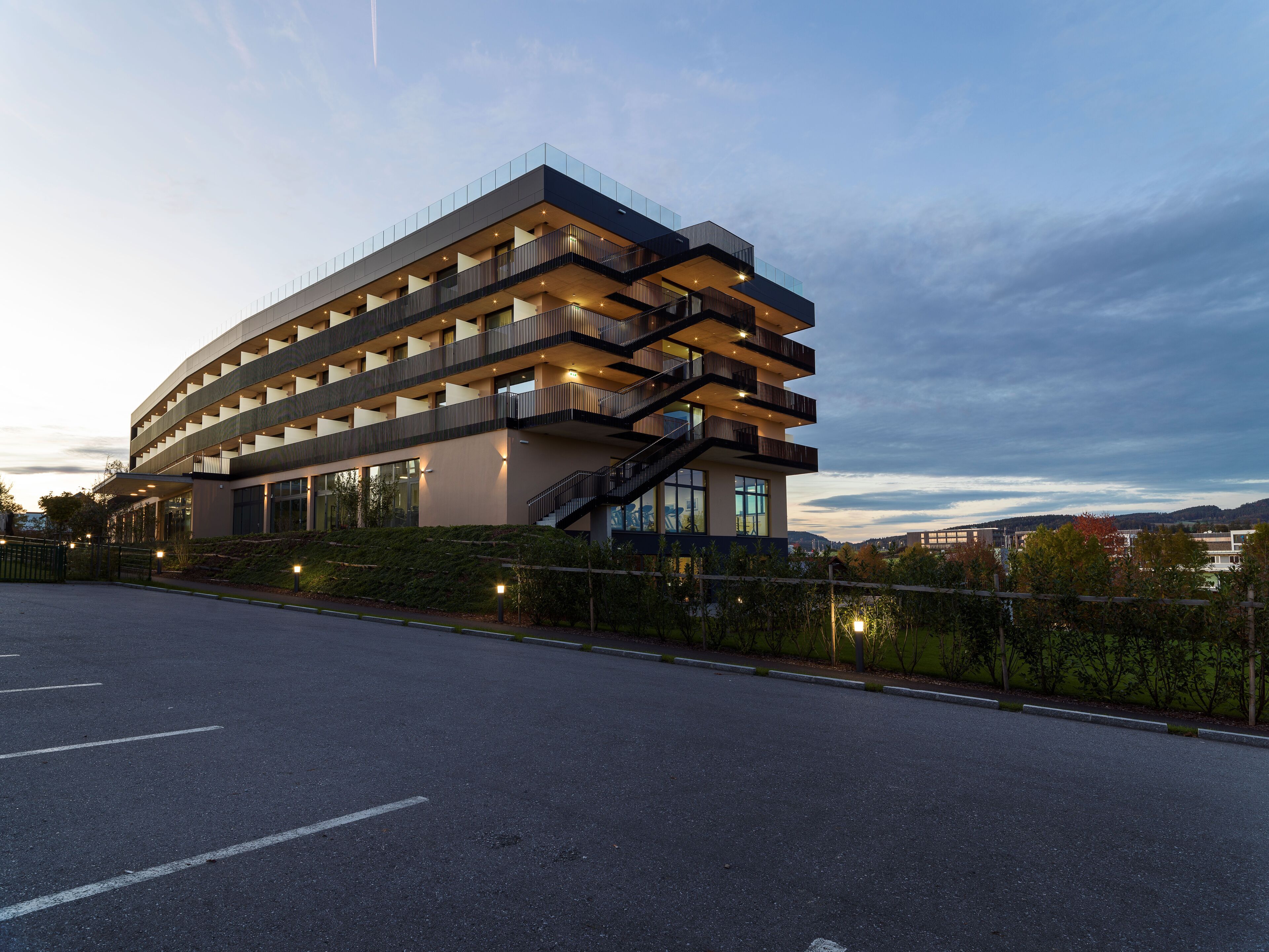 A modern multi-story building with a unique architectural design, featuring balconies and staircases.