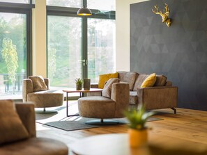 Ein modernes Wohnzimmer mit Sofa, Sesseln, einem Couchtisch und einem dekorativen Hirschgeweih an der Wand.