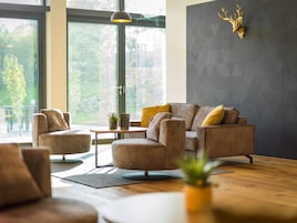 Una sala moderna con un sofá, sillones, una mesa de centro y una cabeza de venado decorativa en la pared.