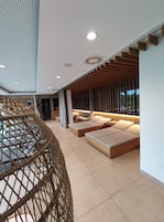 Un interior moderno con una zona de estar que incluye sofás y una silla de fibras naturales.