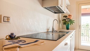 Une cuisine au design moderne, dotée d’un évier en acier inoxydable, d’un four encastré et d’un crédence. Un vase rempli de fleurs est posé sur le comptoir, et une serviette est placée sur l’évier.