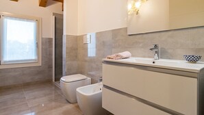 Une salle de bain moderne avec un grand miroir, un lavabo, des toilettes et un bidet.
