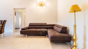 Un salon moderne avec un canapé d’angle, une lampe sur pied et un luminaire au plafond.