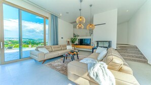 Una sala de estar moderna con un sofá grande, una mesa de centro y un televisor. Hay una escalera que conduce a un nivel superior.