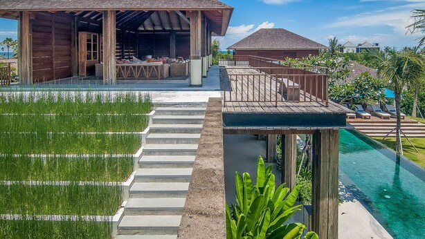 Un resort con un pabellón de madera, una piscina y una escalera que conduce a una terraza.